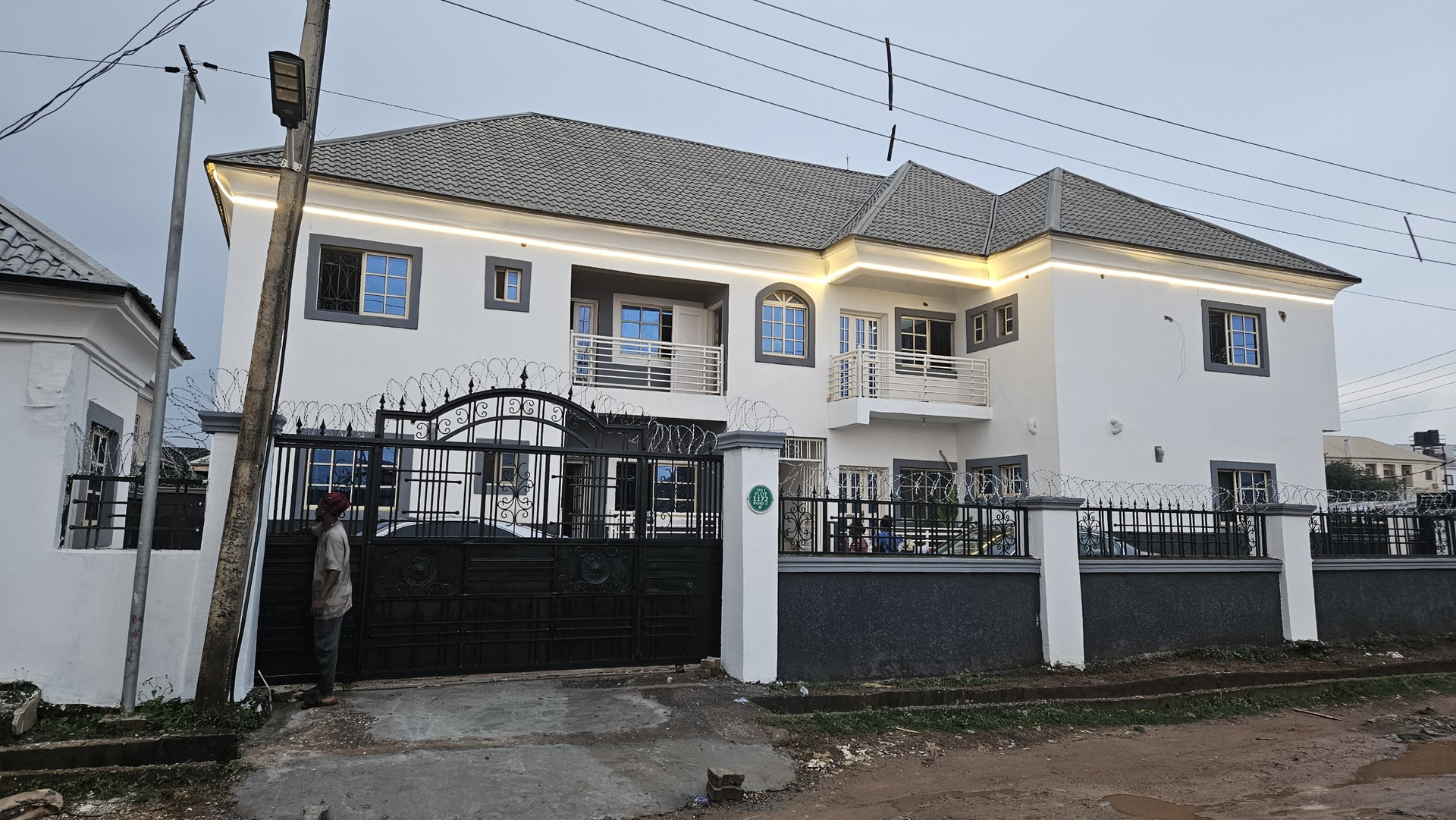 Front view of Jonah's Place, a two-storey white building with grey window trims, in Lugbe, Abuja